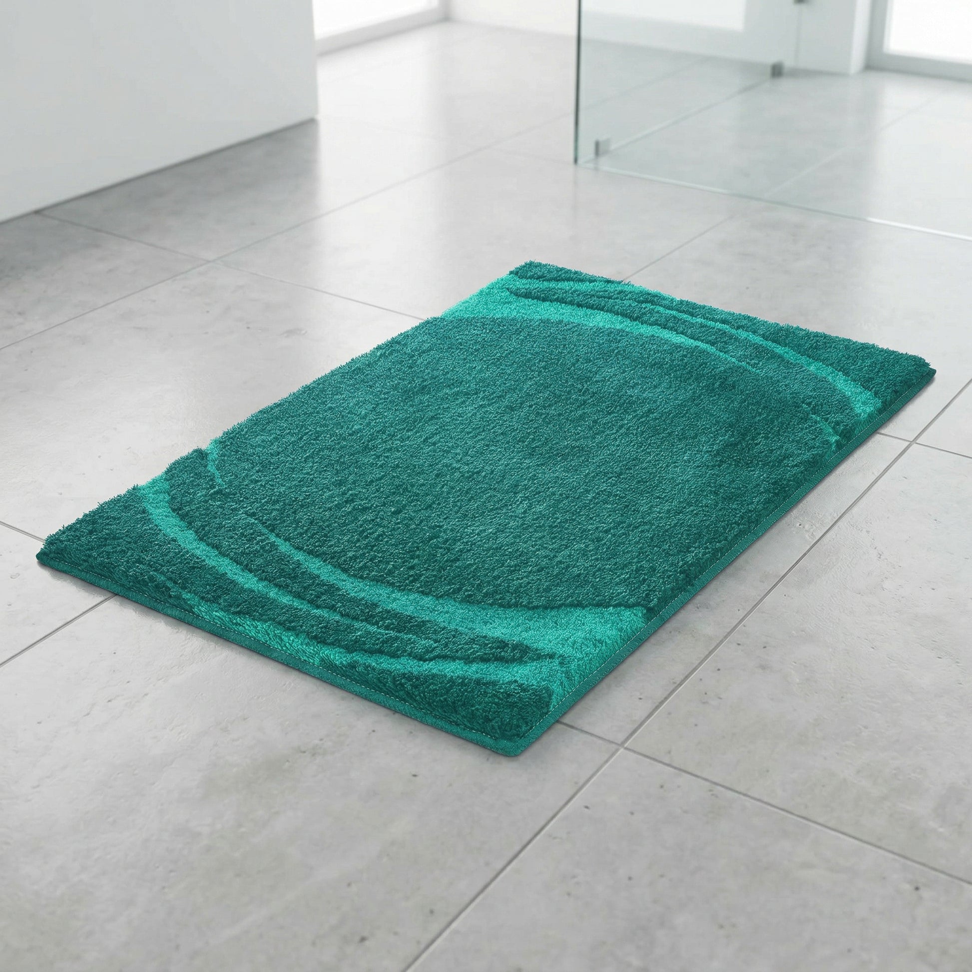 Türkisgrüne Badematte mit dezentem Wellenmuster auf Fliesenboden im Bad