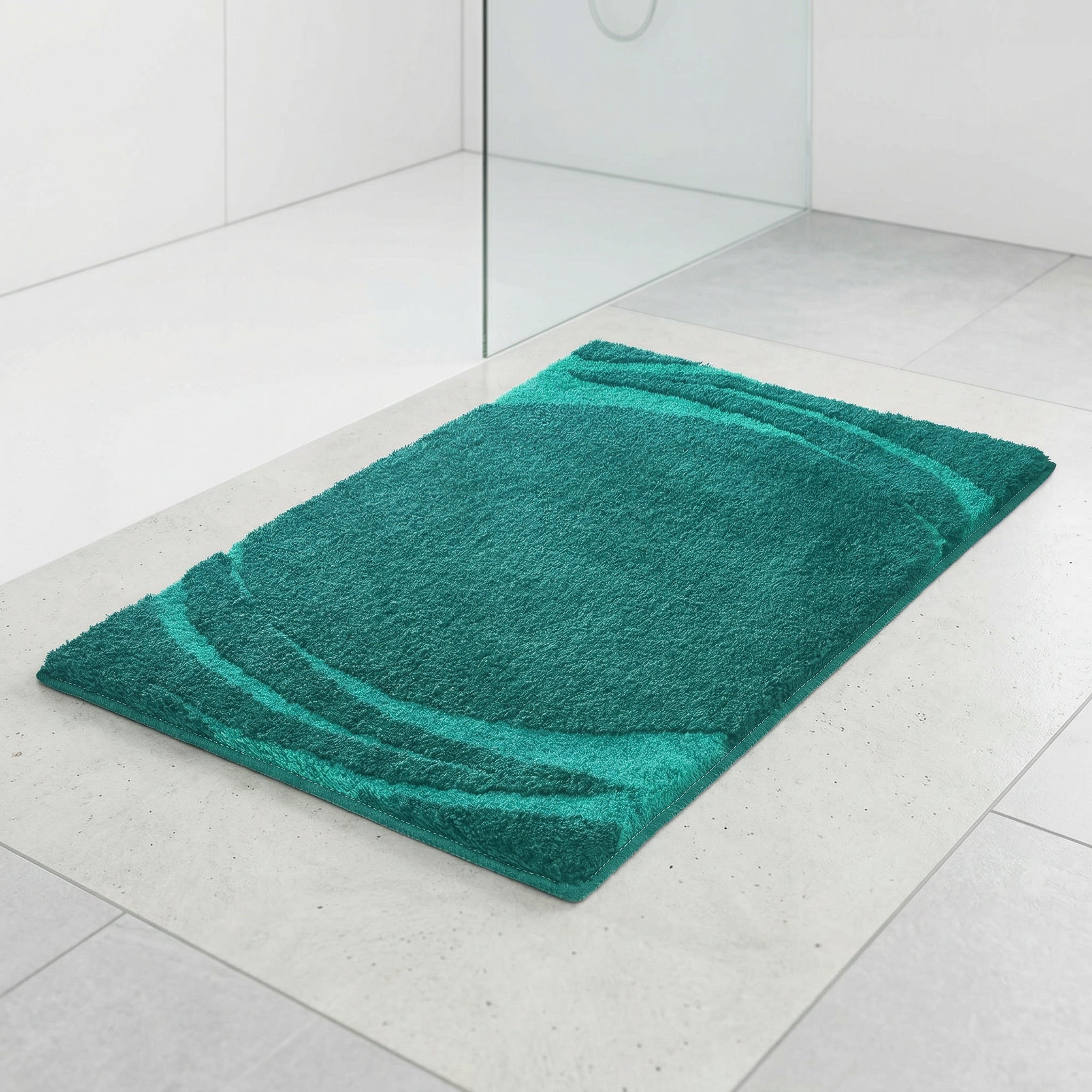 Rechteckige petrolfarbene Badematte auf hellen Fliesen im modernen Bad