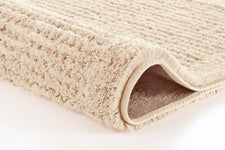 Beiger, weicher Badematte-Teppich in Nahaufnahme, leicht gerollt