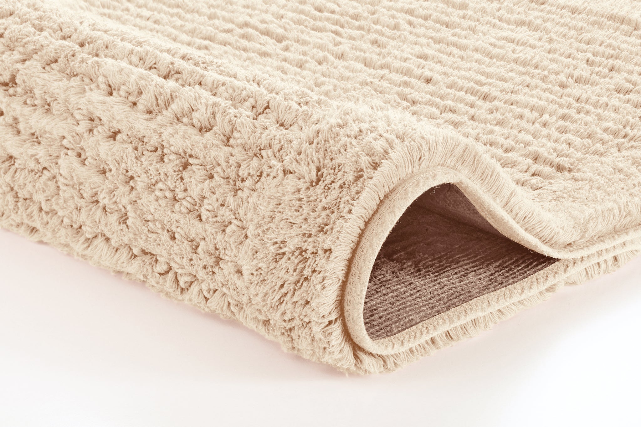 Badteppich NET Natur 60 x 60 cm liegt zusammengerollt und zeigt seine weiche Struktur.