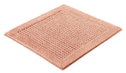 Badteppich NET Papaya 60 x 60 cm liegt als quadratischer, strukturierter Teppich auf hellem Untergrund.