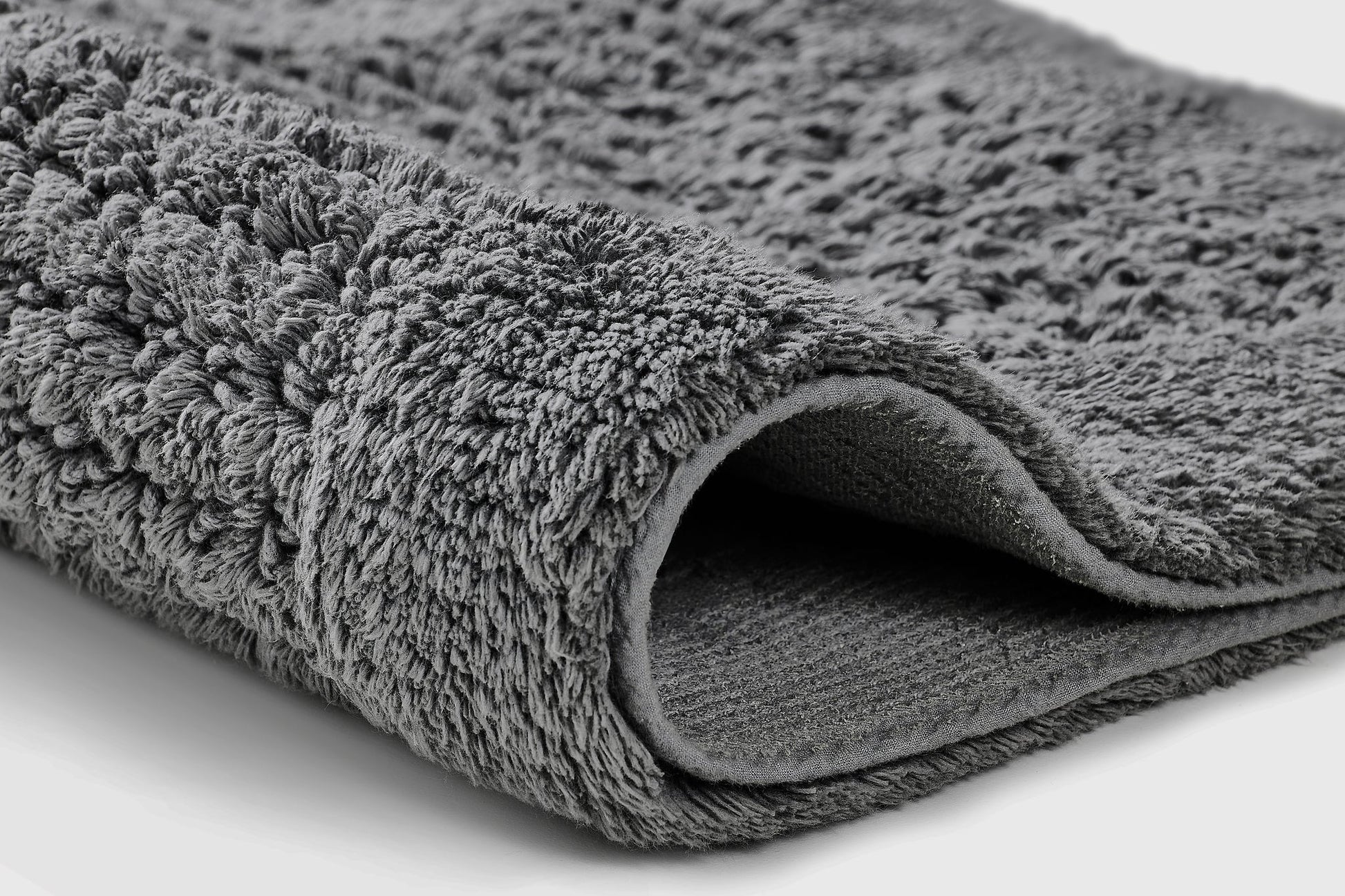 Badteppich NET Schiefer 70 x 120 cm liegt detailreich gefaltet auf hellem Untergrund.