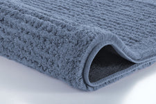 Gefaltete blaue Badematte mit flauschiger, gerippter Oberfläche aus Stoff