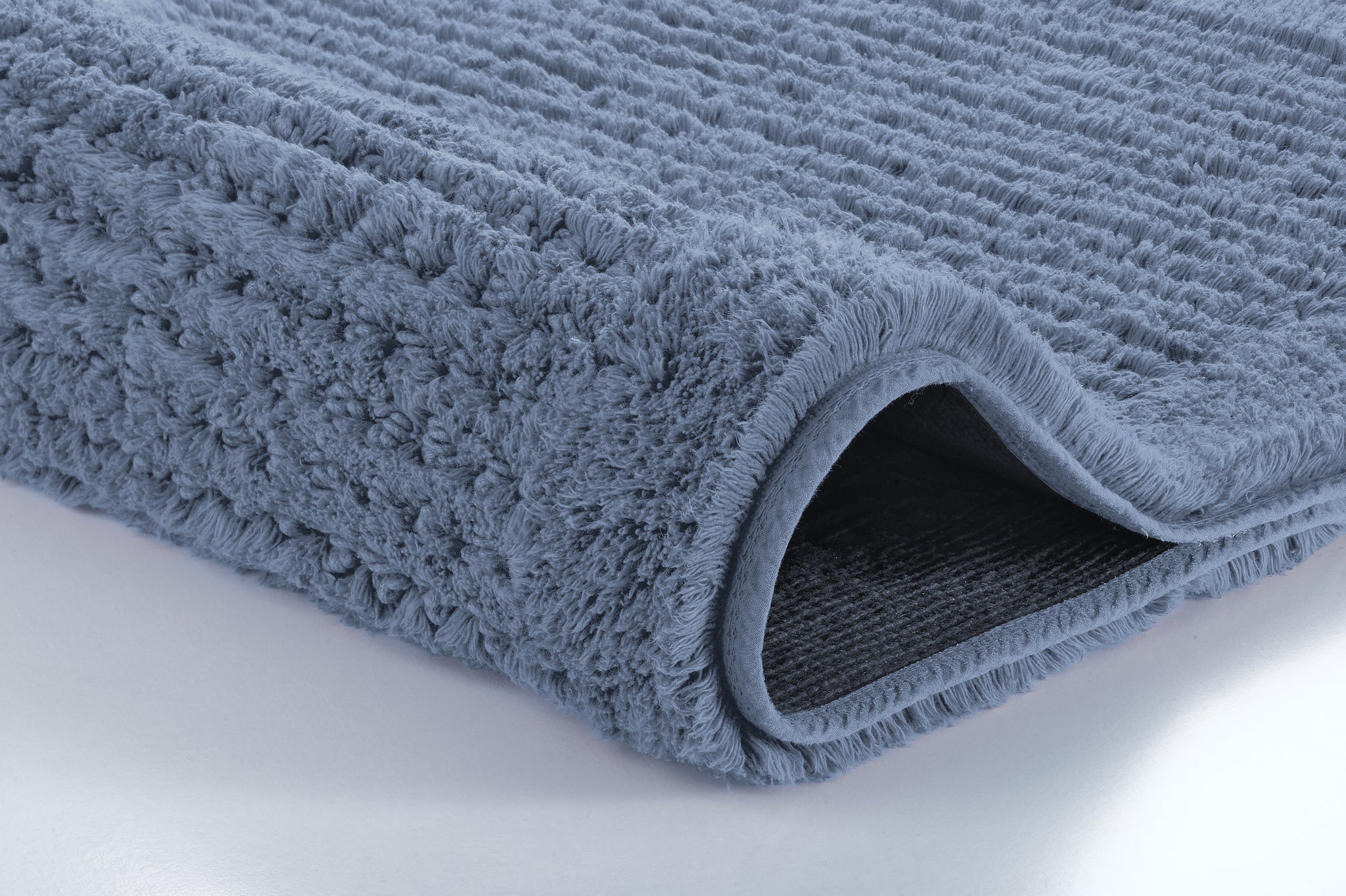 Badteppich NET in Stahlblau 70 x 120 cm zeigt weiche Struktur und umgeschlagene Kante.