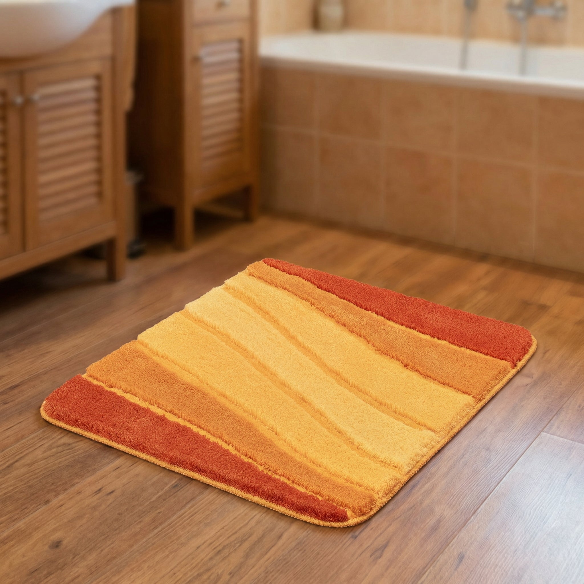 Weicher Badematte in Orange-Gelb auf Holzfußboden vor Badewanne im Bad
