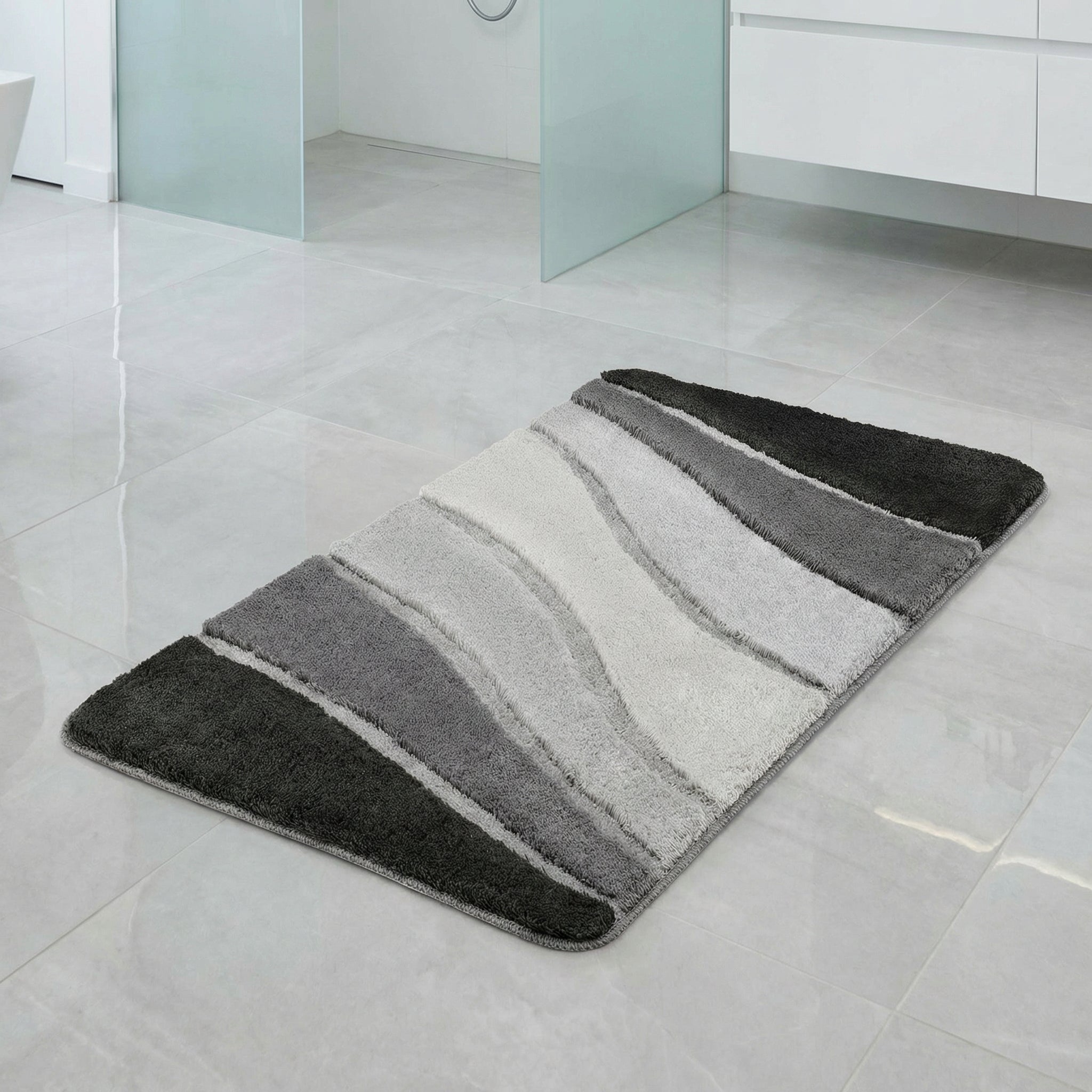 Rechteckiger Badteppich in Grau- und Weißtönen auf hellen Fliesen