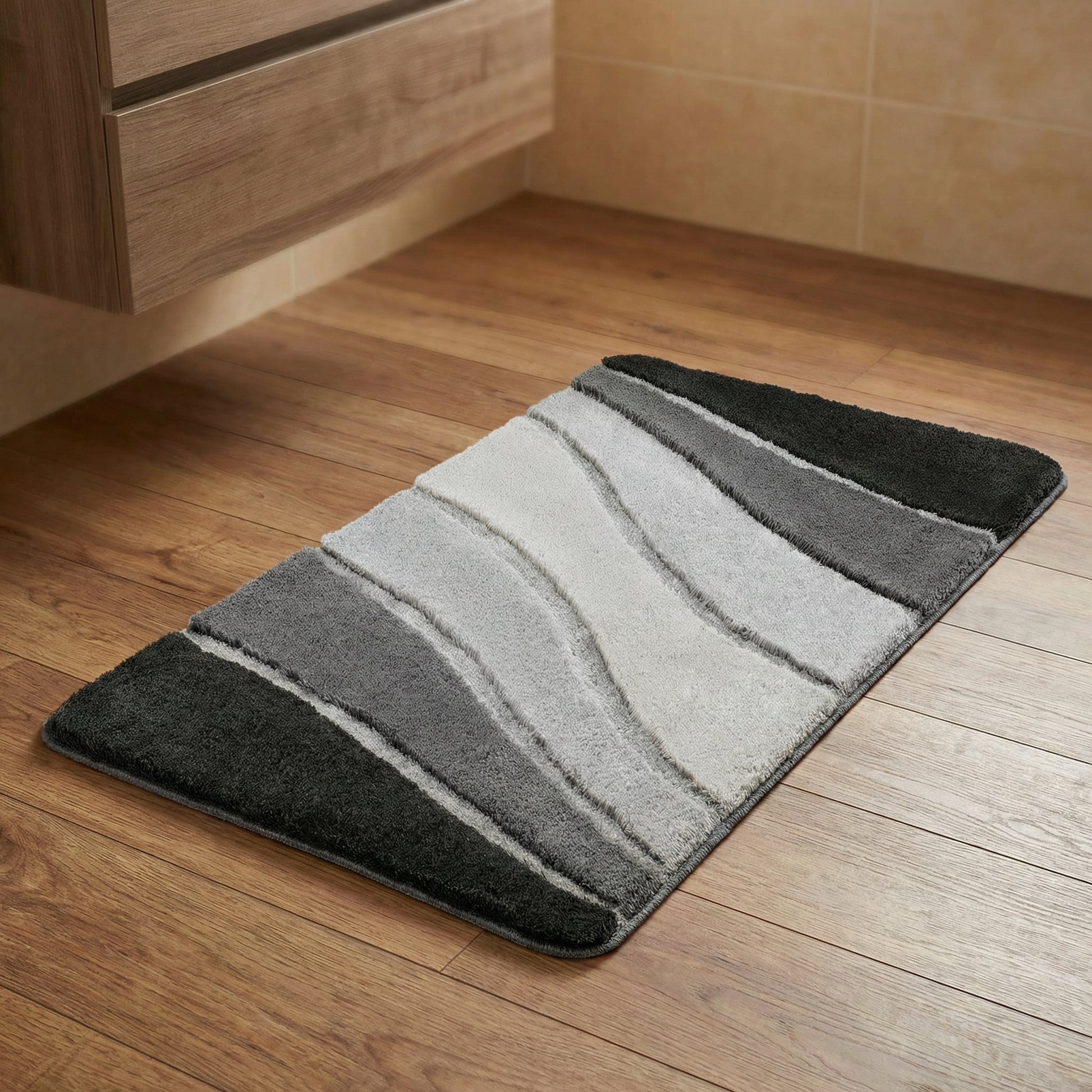 Rechteckige Badematte mit grau-weißen Wellen auf Holzfußboden im Bad
