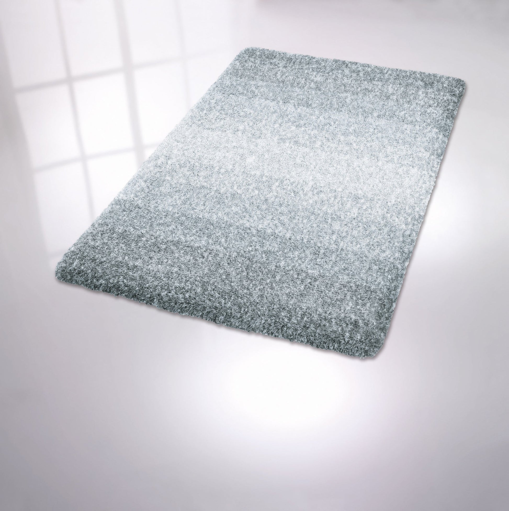 Rechteckige hellgraue Badematte mit flauschiger Oberfläche auf Boden