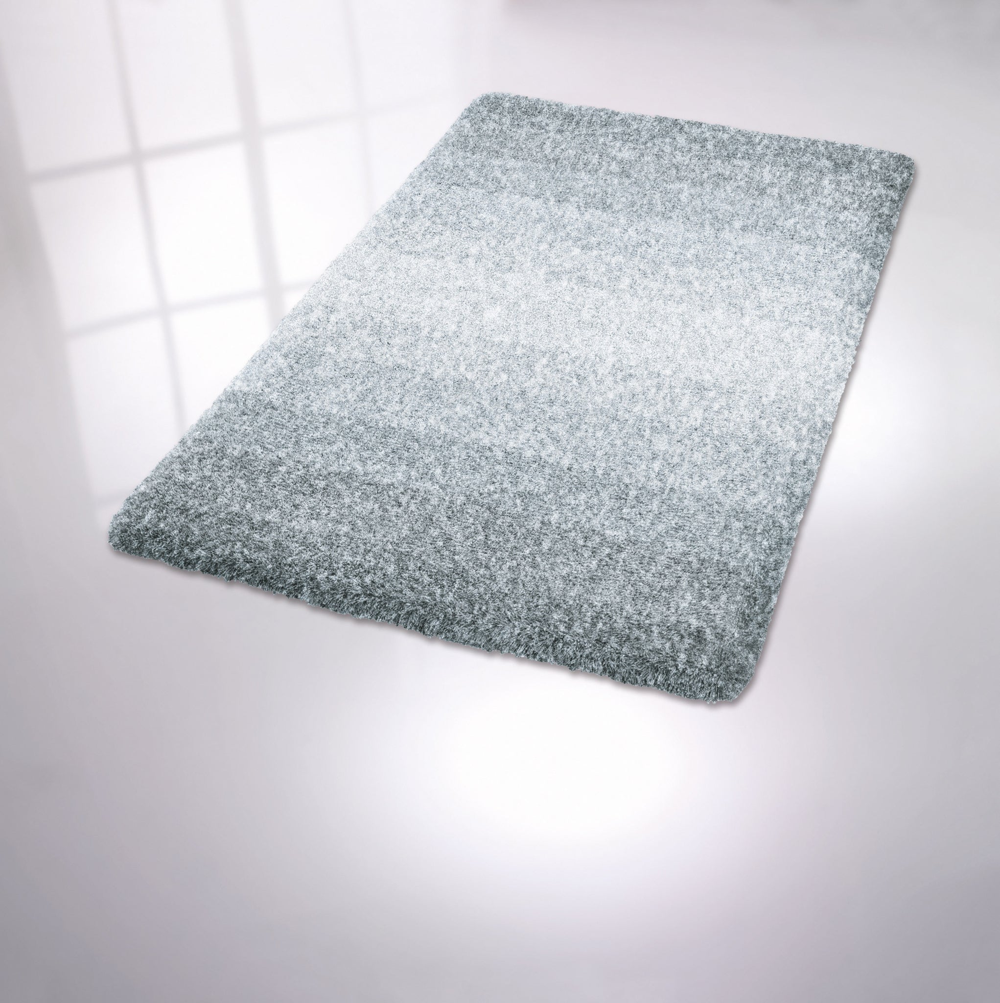 Rechteckige hellgraue Badematte mit flauschiger Oberfläche auf Boden