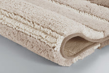 Gefaltete beige Badematte mit weicher Hoch-Tief-Struktur in Nahaufnahme