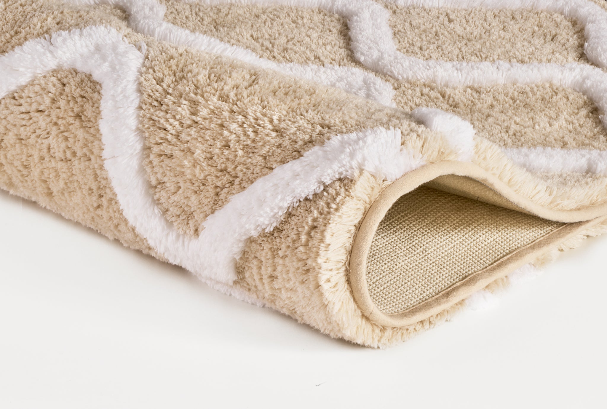 Badteppich PIANA Sandbeige 55 x 65 cm mit weißem Muster, Detailansicht eingerollte Ecke.