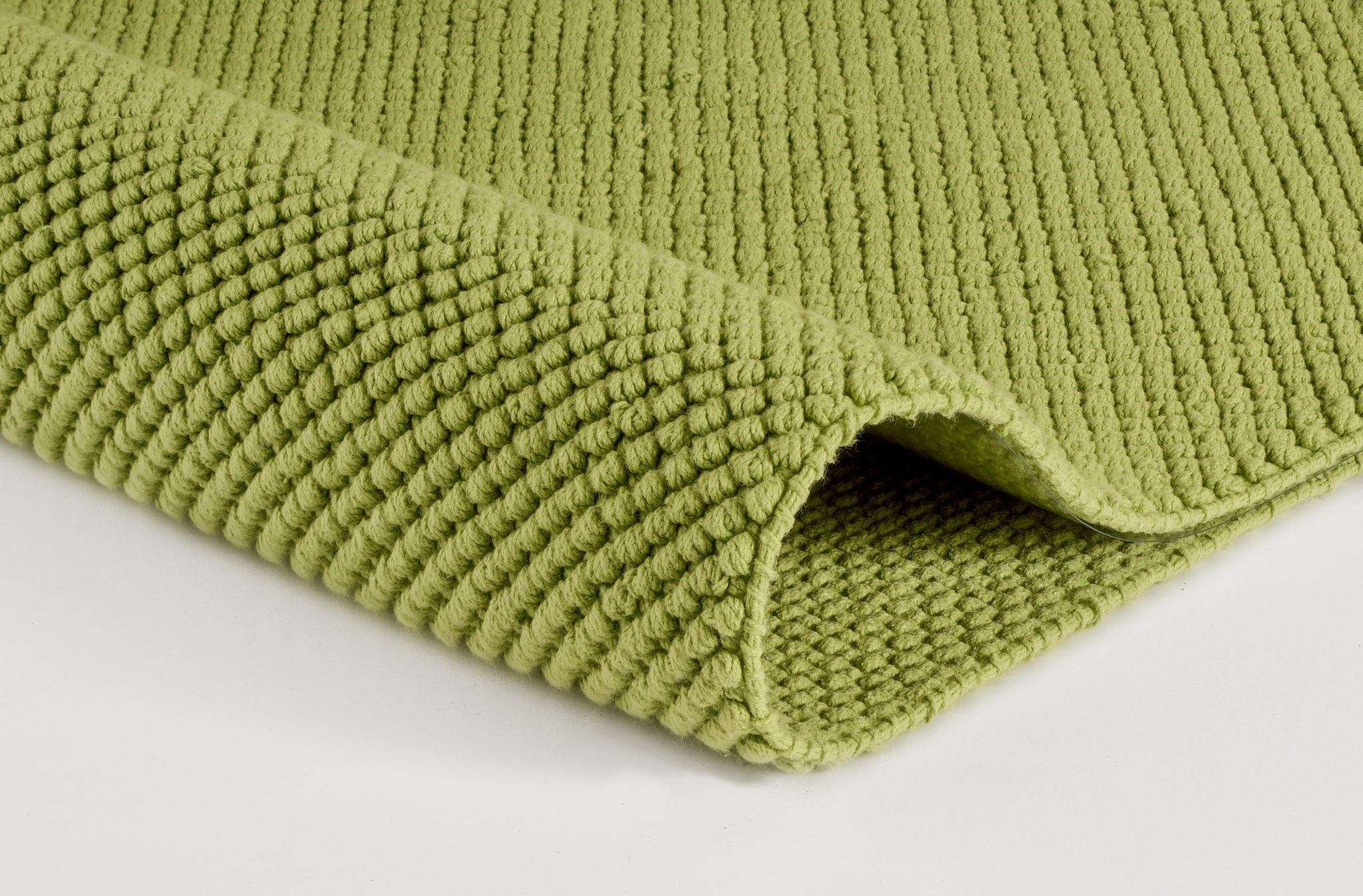 Grüne, strukturierte Badematte aus Textil in Nahaufnahme schräg oben