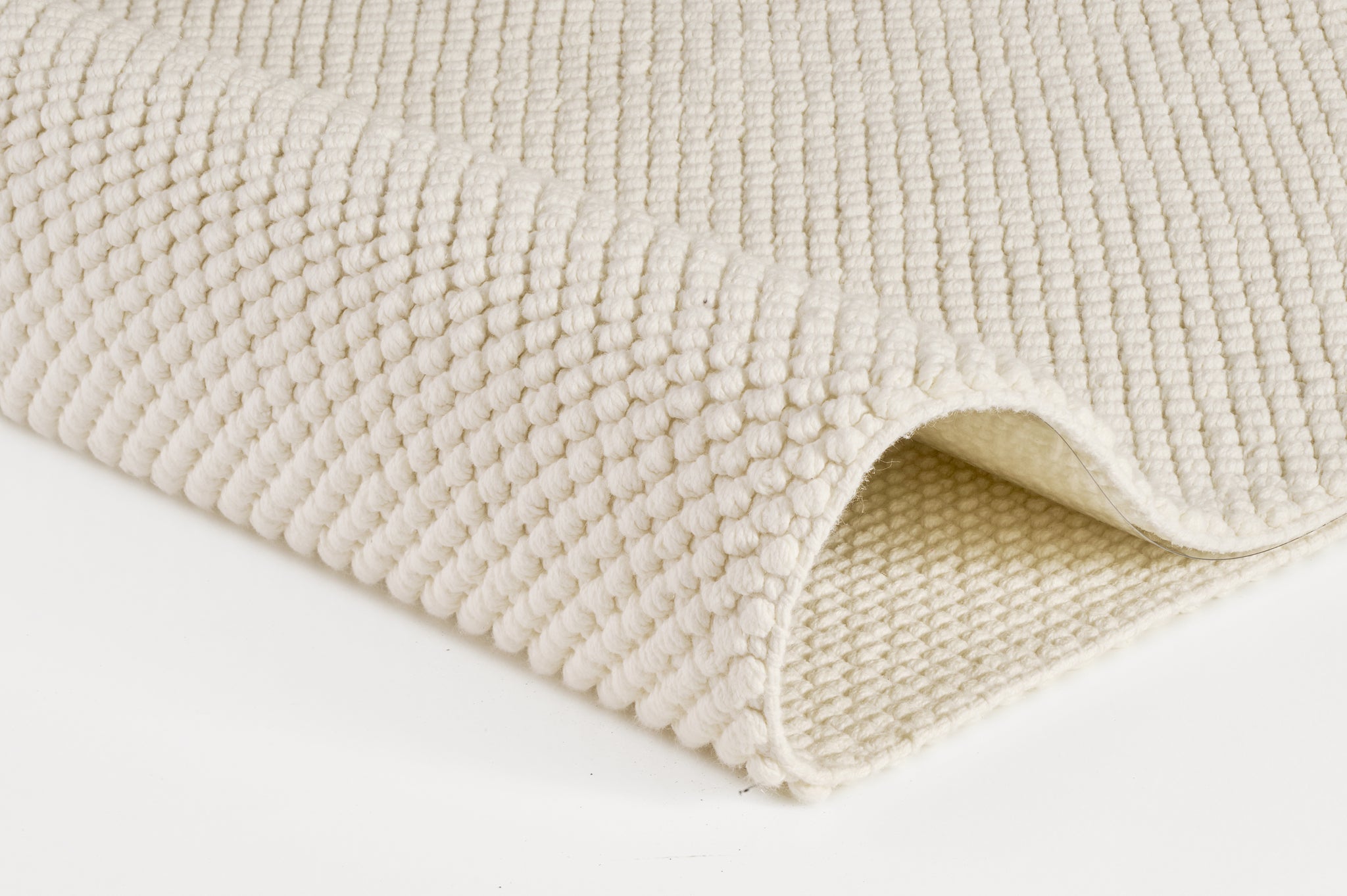 Cremefarbener, grob strukturierter Badteppich mit umgeschlagener Ecke