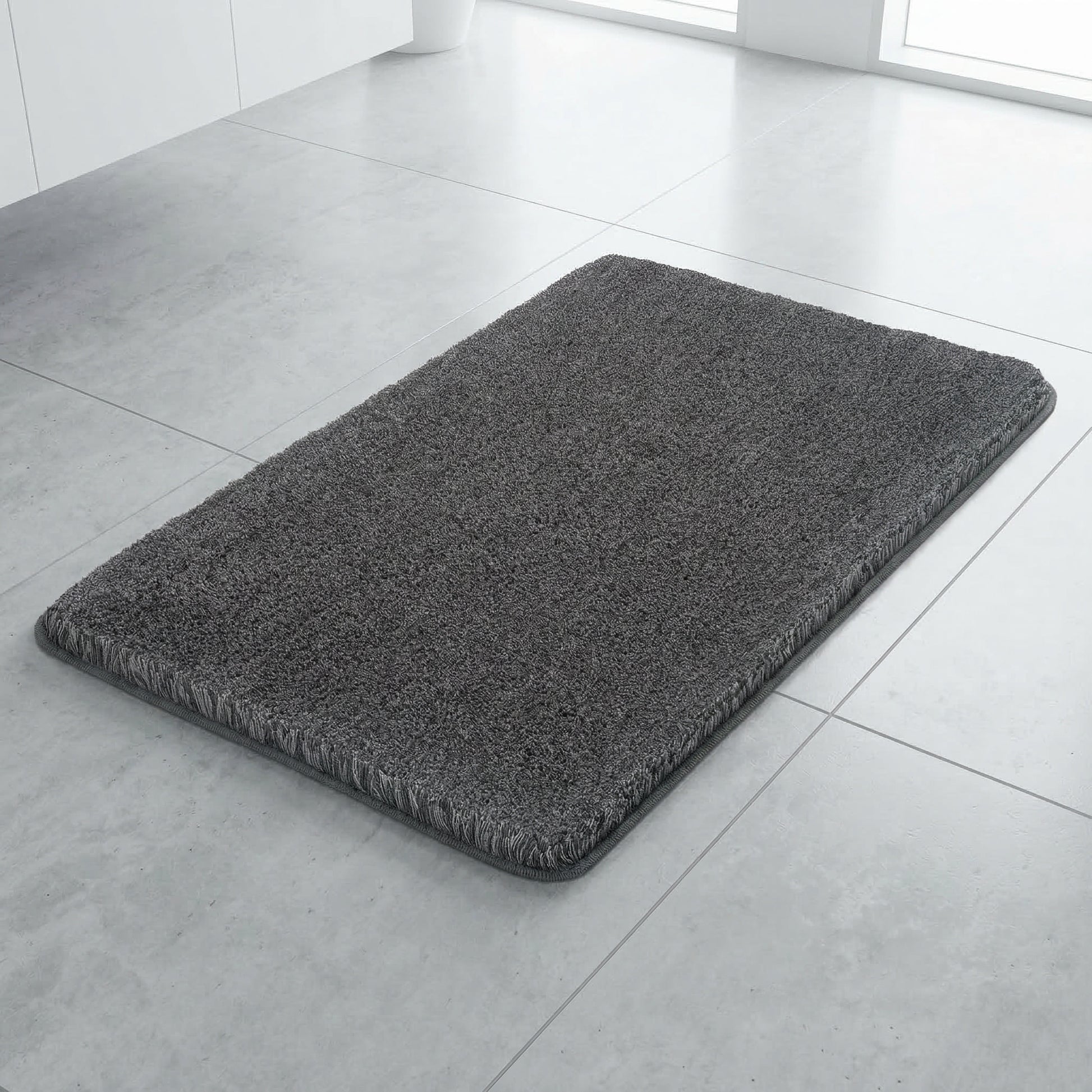 Dunkelgrauer Badteppich auf hellem Fliesenboden im modernen Bad