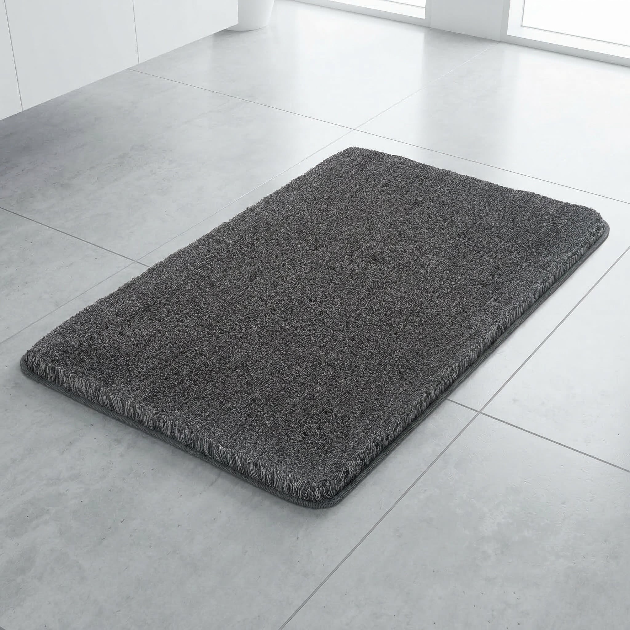 Dunkelgrauer Badteppich auf hellem Fliesenboden im modernen Bad