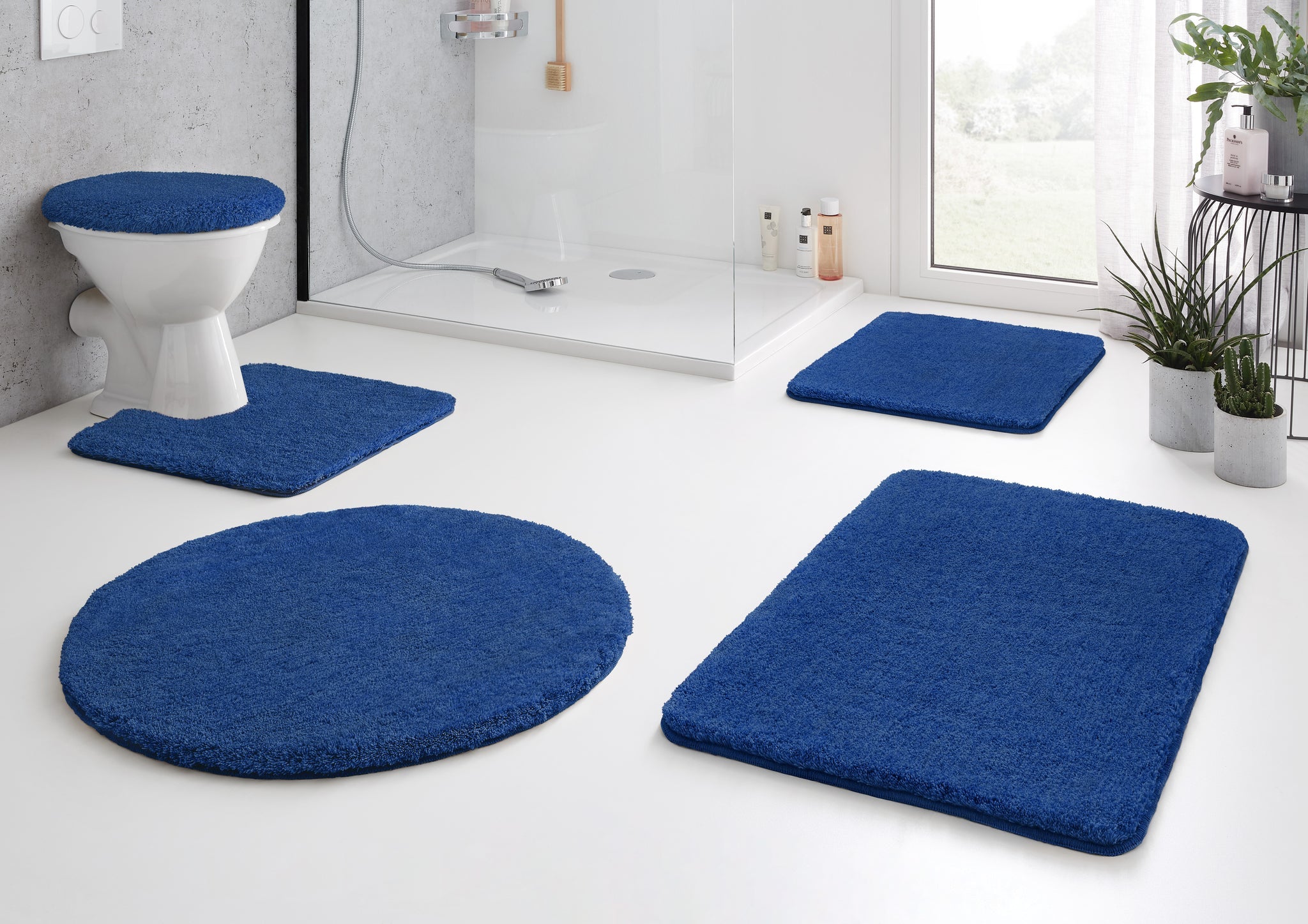 Modernes Bad mit blauen Badteppichen und WC-Deckelbezug aus Textil