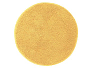 Runder, flauschiger Badteppich in warmem Gelbton von oben fotografiert