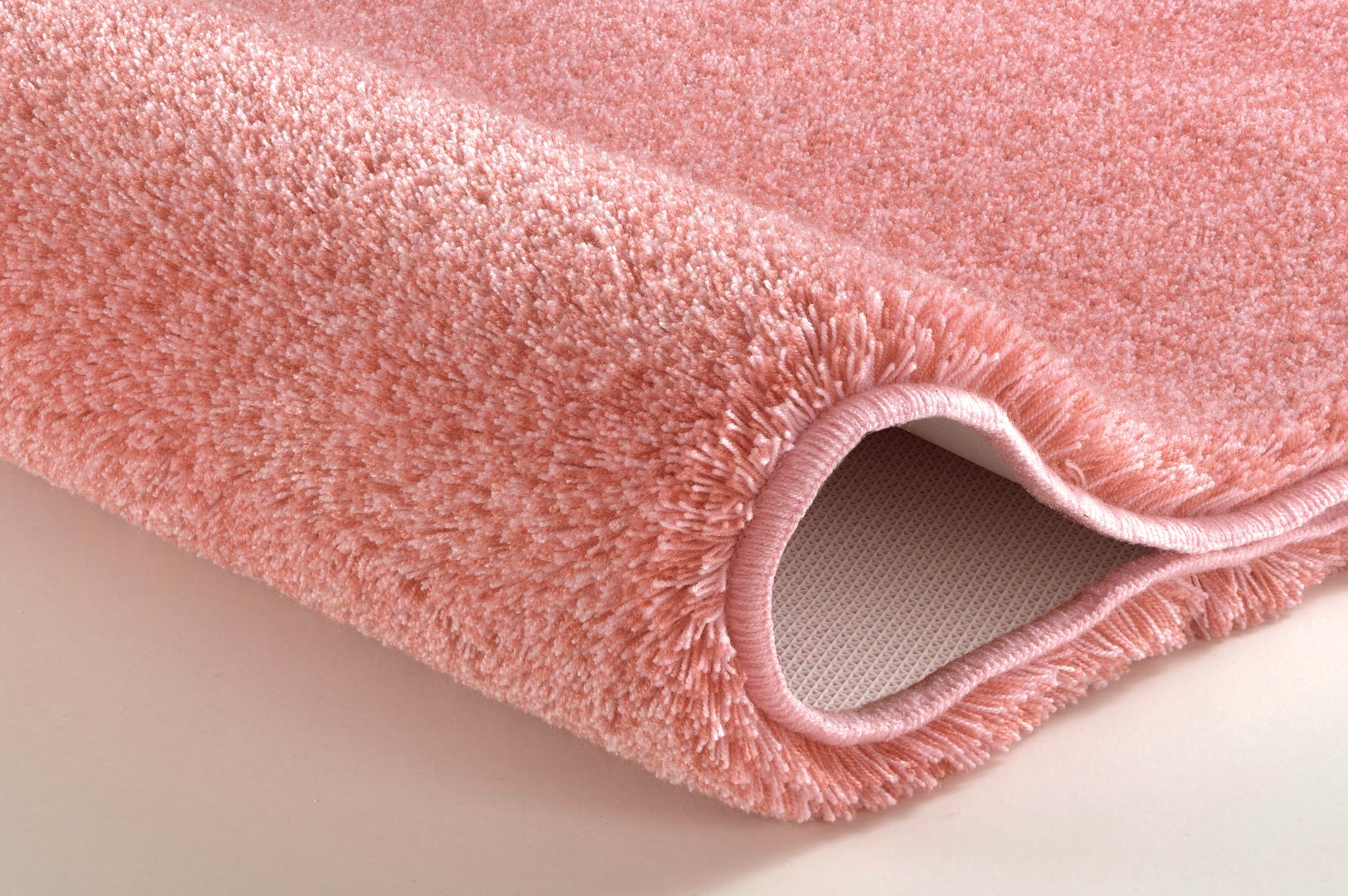 Nahaufnahme rosa Badematte mit weichem, hochflorigem Teppichrand