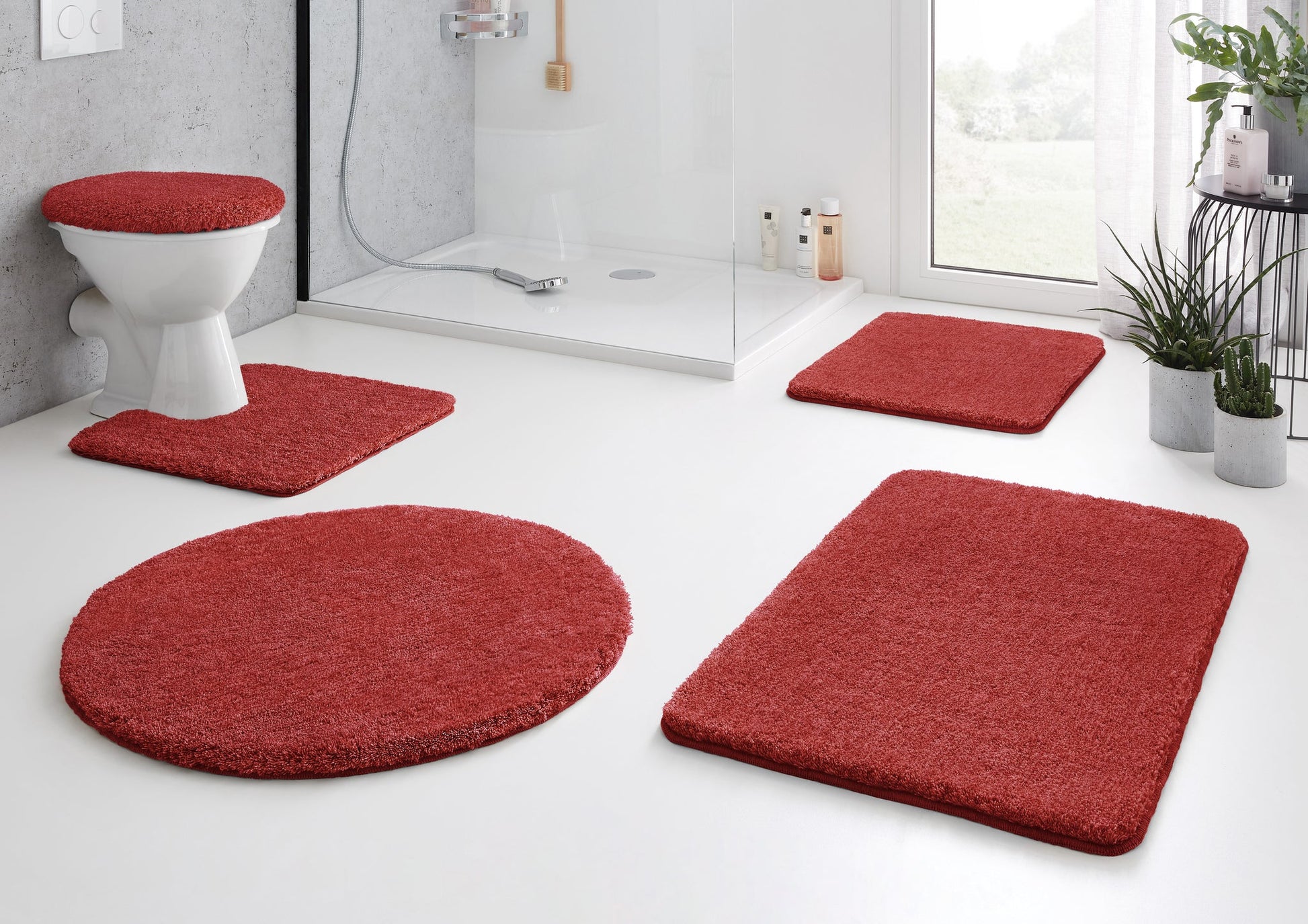 Rotes Badteppich-Set vor Dusche und WC auf weißem Badezimmerboden