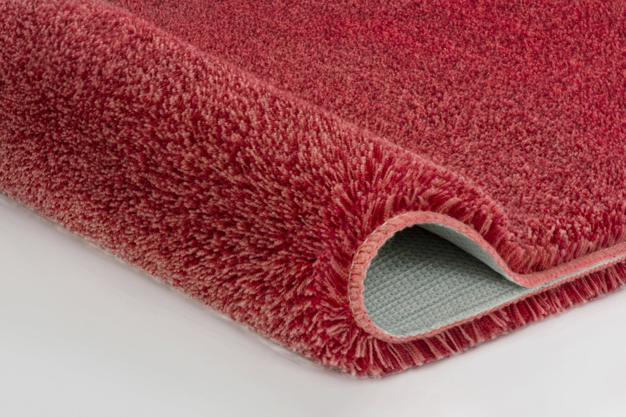 Nahaufnahme einer roten Badematte mit umgeschlagener Ecke vorn