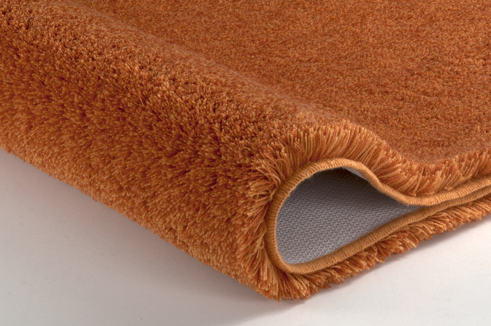 Nahaufnahme einer orangen Badematte mit umgeschlagener Kante vorn