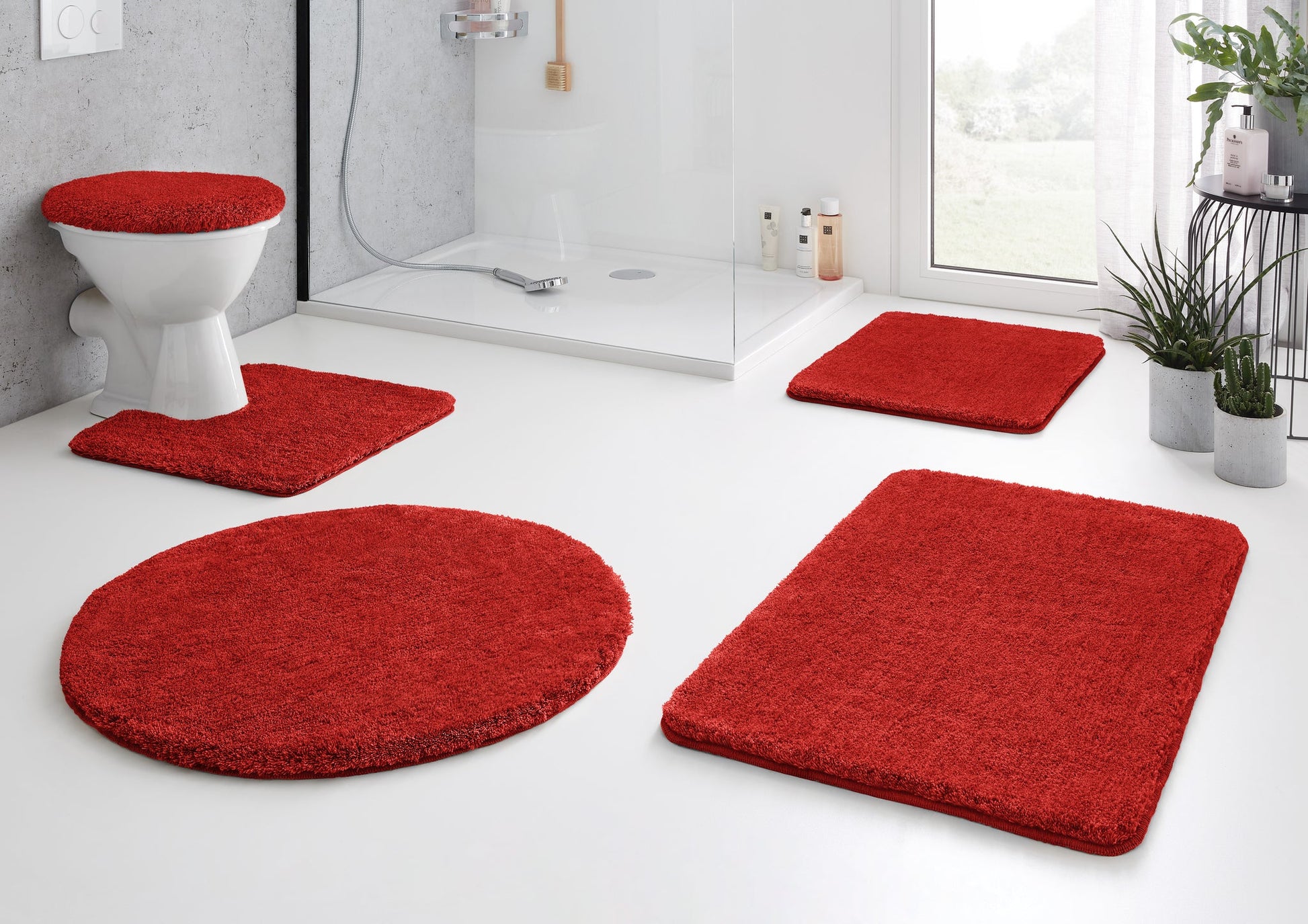 Rotes Badteppich-Set auf hellem, modernem Badboden mit Dusche und WC