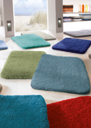 Mehrere einfarbige Badteppiche in türkis, verschiedenen Blautönen, Rot, Anthrazit in einem hellen Show-Raum
