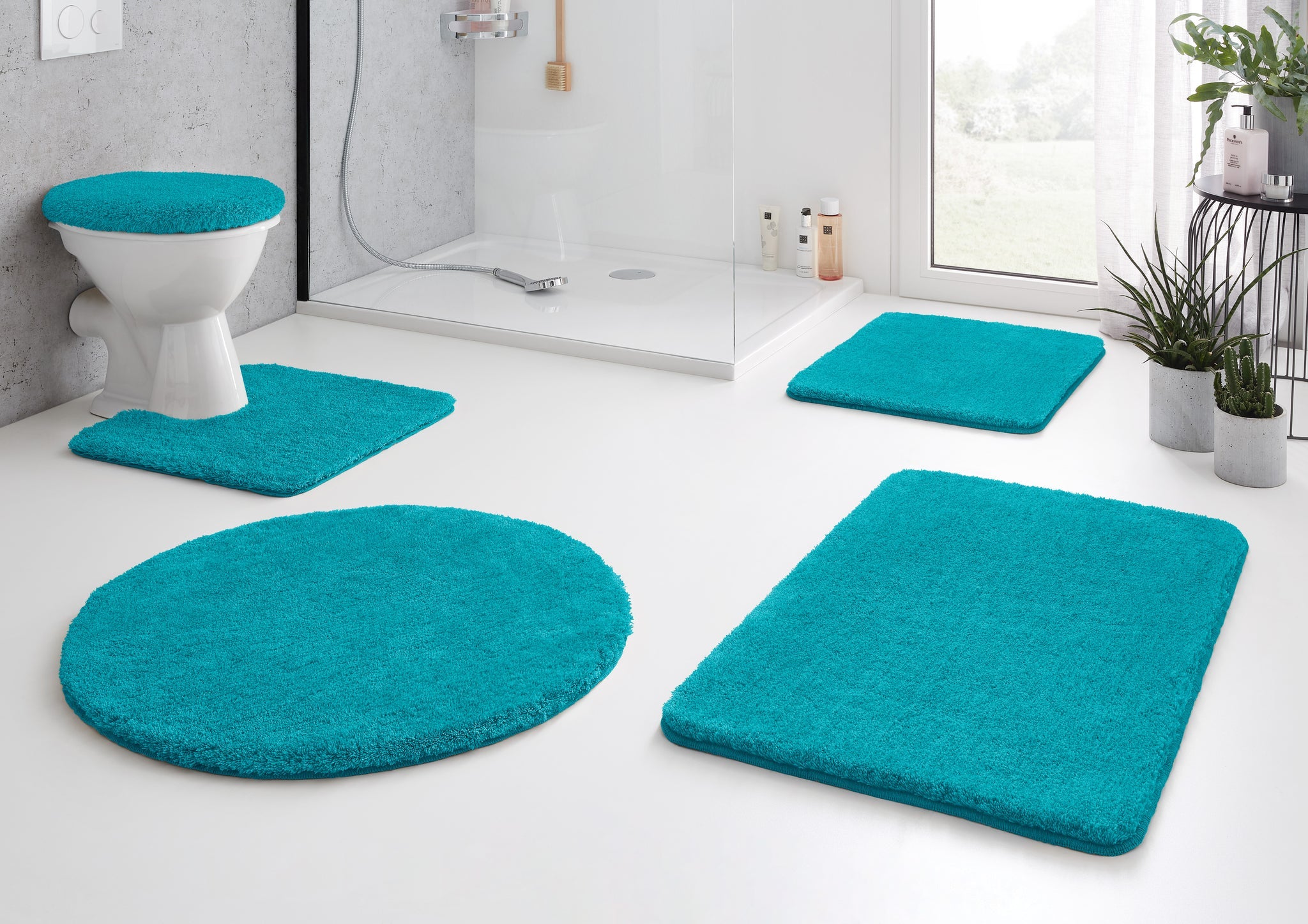 Badteppich RELAX Türkis 100 cm rund liegt in moderner Badezimmer-Einrichtung.