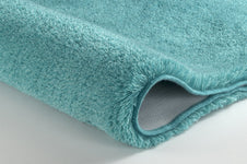 Nahaufnahme türkisfarbener Badematte mit hochflorigem, weichem Flor