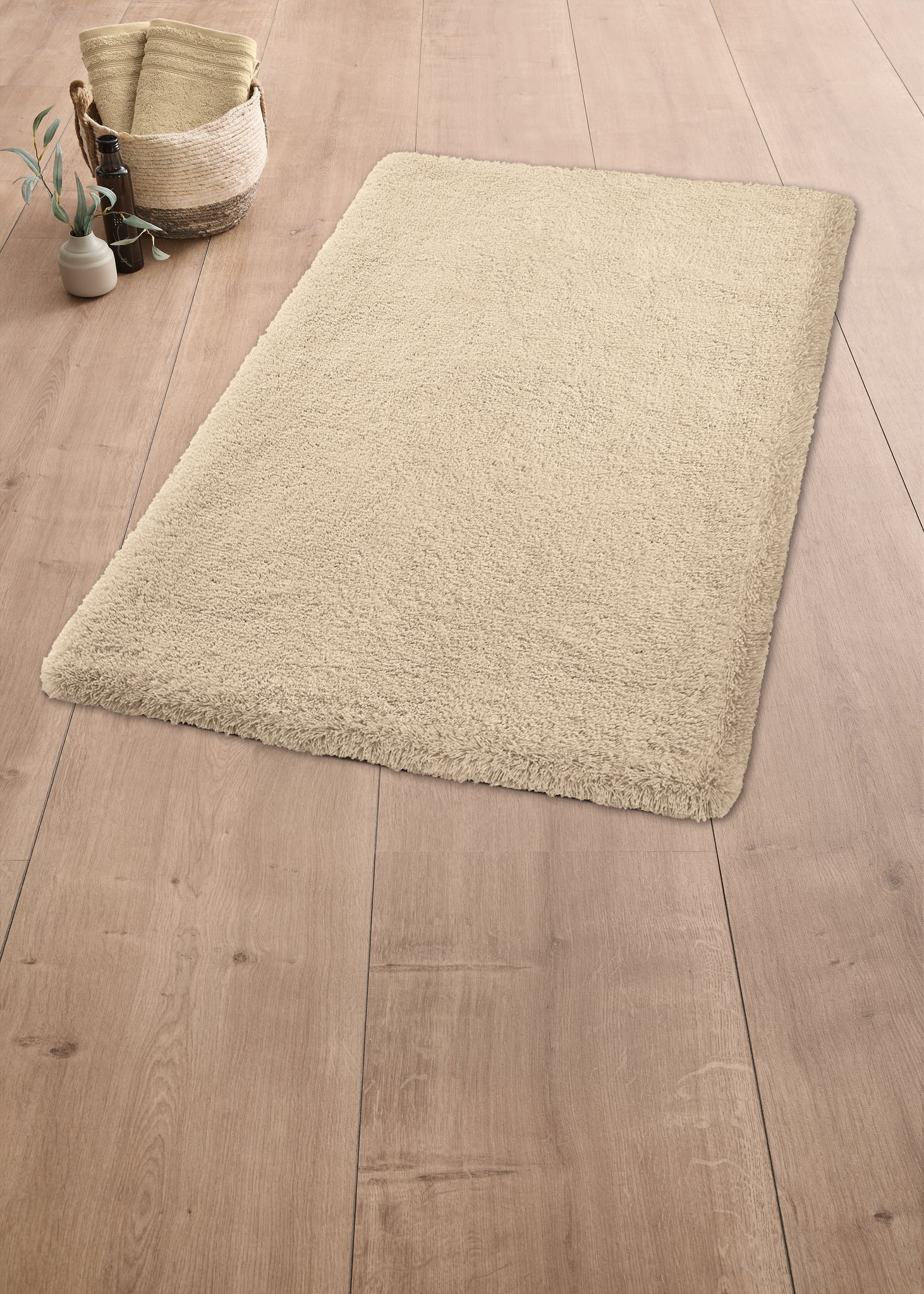 Beiger rechteckiger Badezimmerteppich auf hellem Holzfußboden liegend