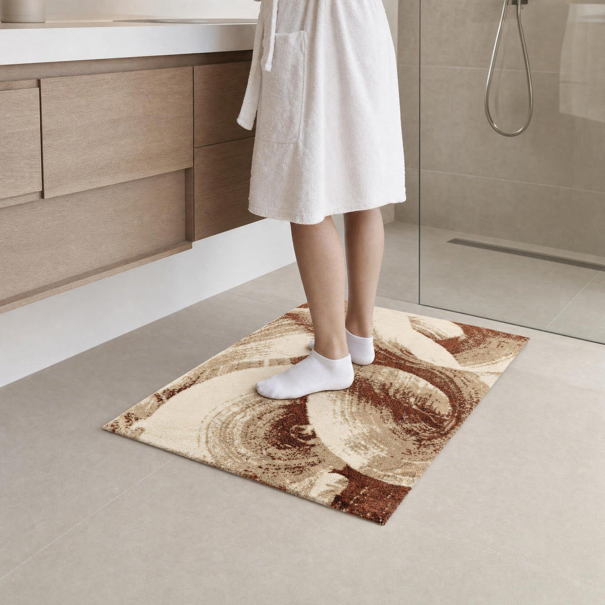 Person im Bademantel steht auf gemustertem Badteppich im Badezimmer.