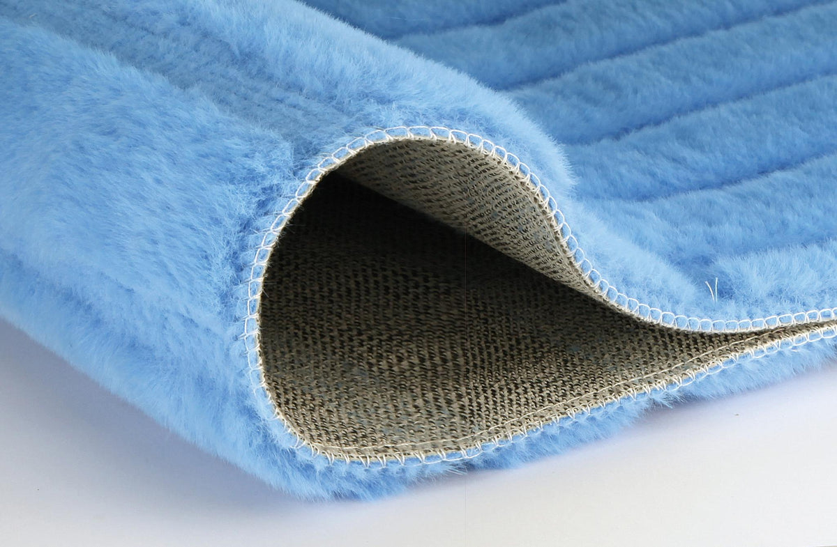 Nahaufnahme einer hellblauen, flauschigen Matte mit umgeschlagener Ecke.