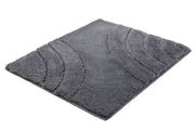 Badteppich SATURN in Anthrazit 55 x 65 cm liegt flach mit gebogenen Konturen auf weißem Hintergrund.