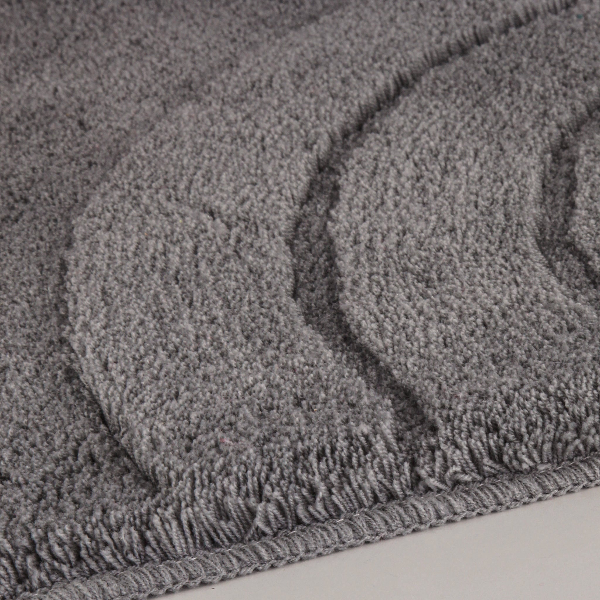 Badteppich SATURN Anthrazit 80 x 140 cm liegt mit reliefierter Struktur auf hellem Boden.