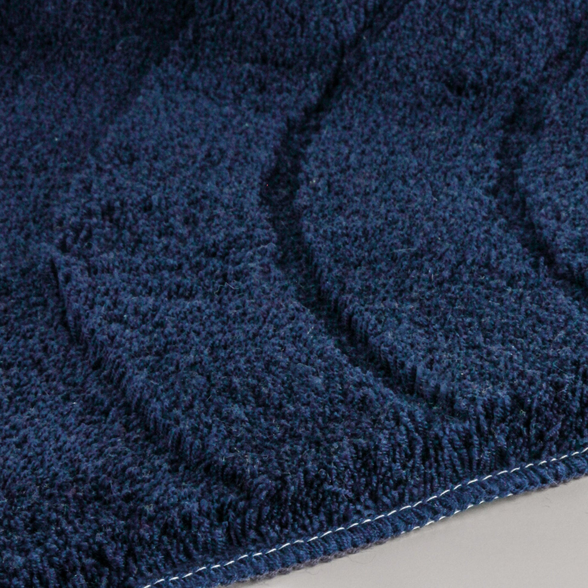 Nahaufnahme des Badteppichs SATURN Navy 55 x 65 cm mit weicher Struktur.