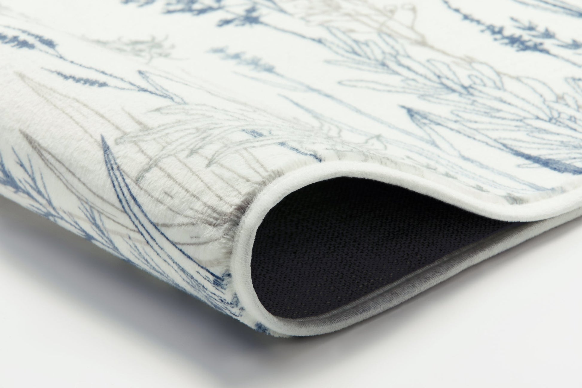 Nahaufnahme einer weißen Badematte mit blauem Pflanzenmuster