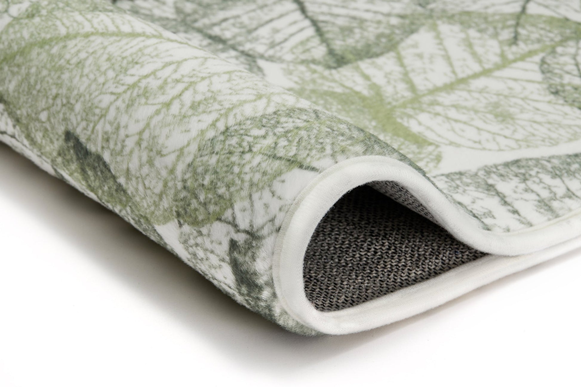 Badteppich SELVA Forest 70 x 120 cm zeigt grüne Blattmuster und aufgerollte Kante in Nahaufnahme.