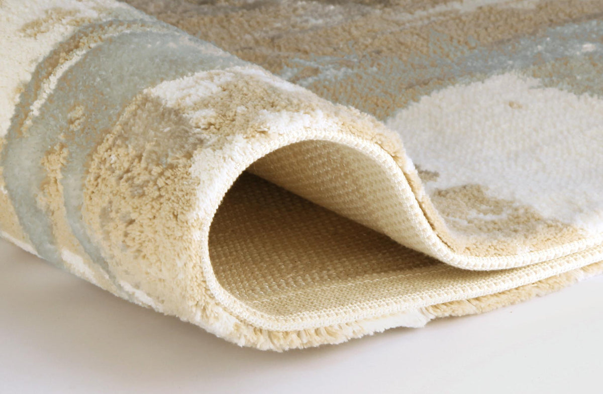 Aufgerollter cremefarbener Teppich mit weicher, flauschiger Oberfläche.