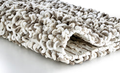Nahaufnahme einer beigen und weißen, flauschigen Badematte mit Schlingen