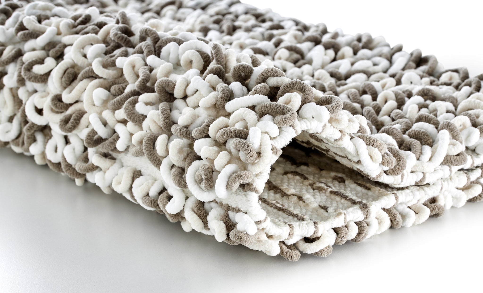 Gefalteter Badteppich SLING Macadamia 60 x 90 cm mit dicker, beiger und weißer Schlingenstruktur.