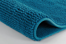 Nahaufnahme einer petrolfarbenen Chenille-Badematte, gerollte Kante