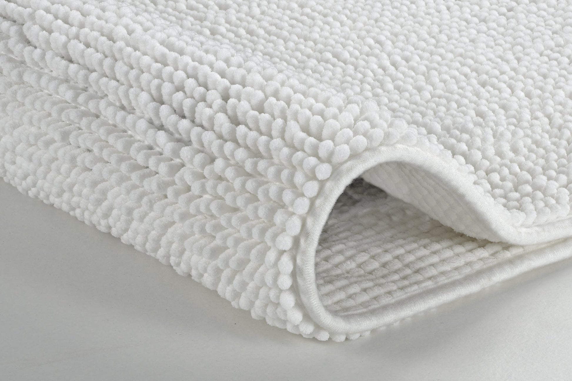 Nahaufnahme einer gefalteten weißen Badematte mit Noppenstruktur
