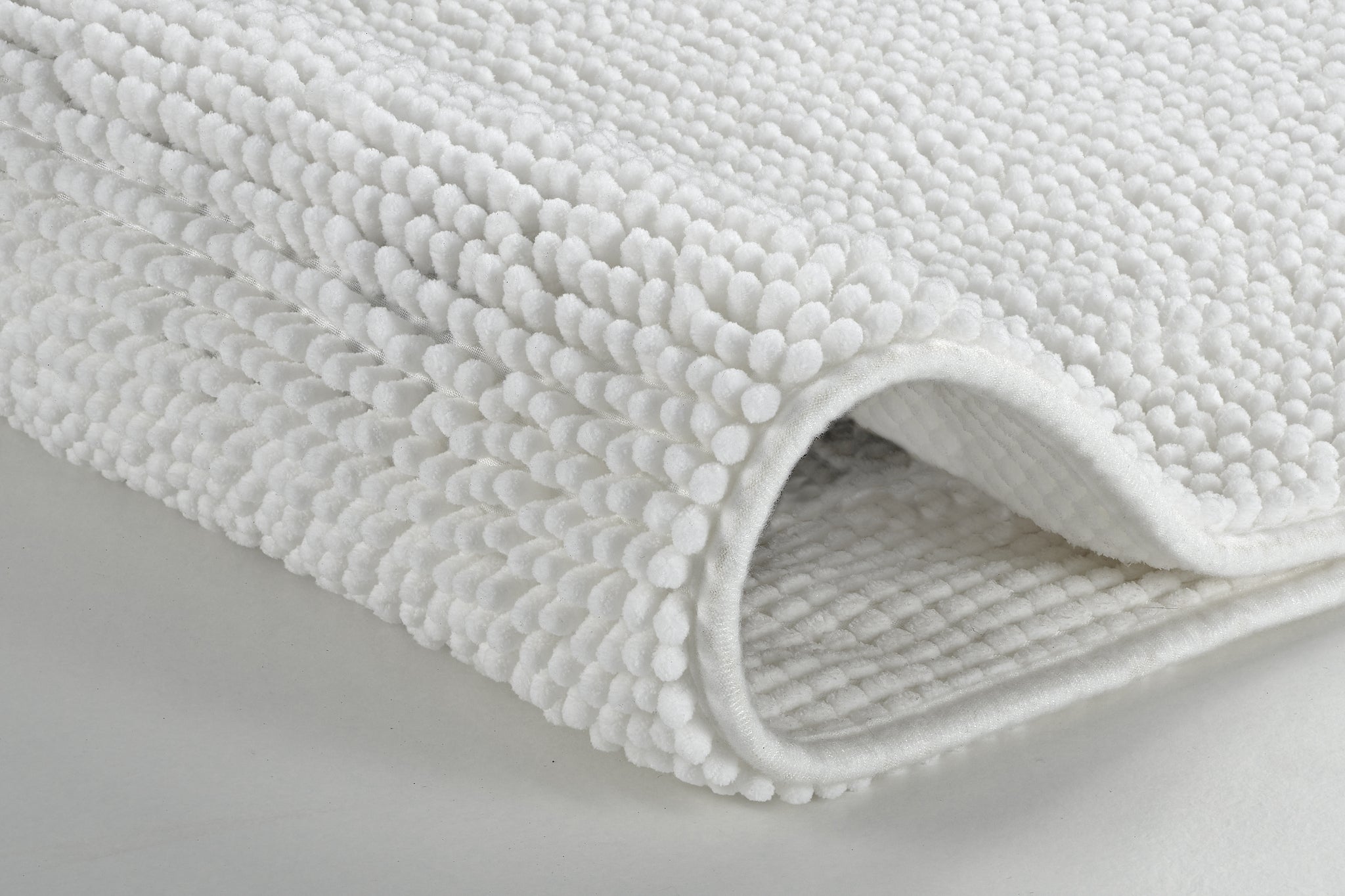 Nahaufnahme einer gefalteten weißen Badematte mit Noppenstruktur