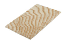 Beige Badematte mit wellenförmigem Muster auf weißem Hintergrund
