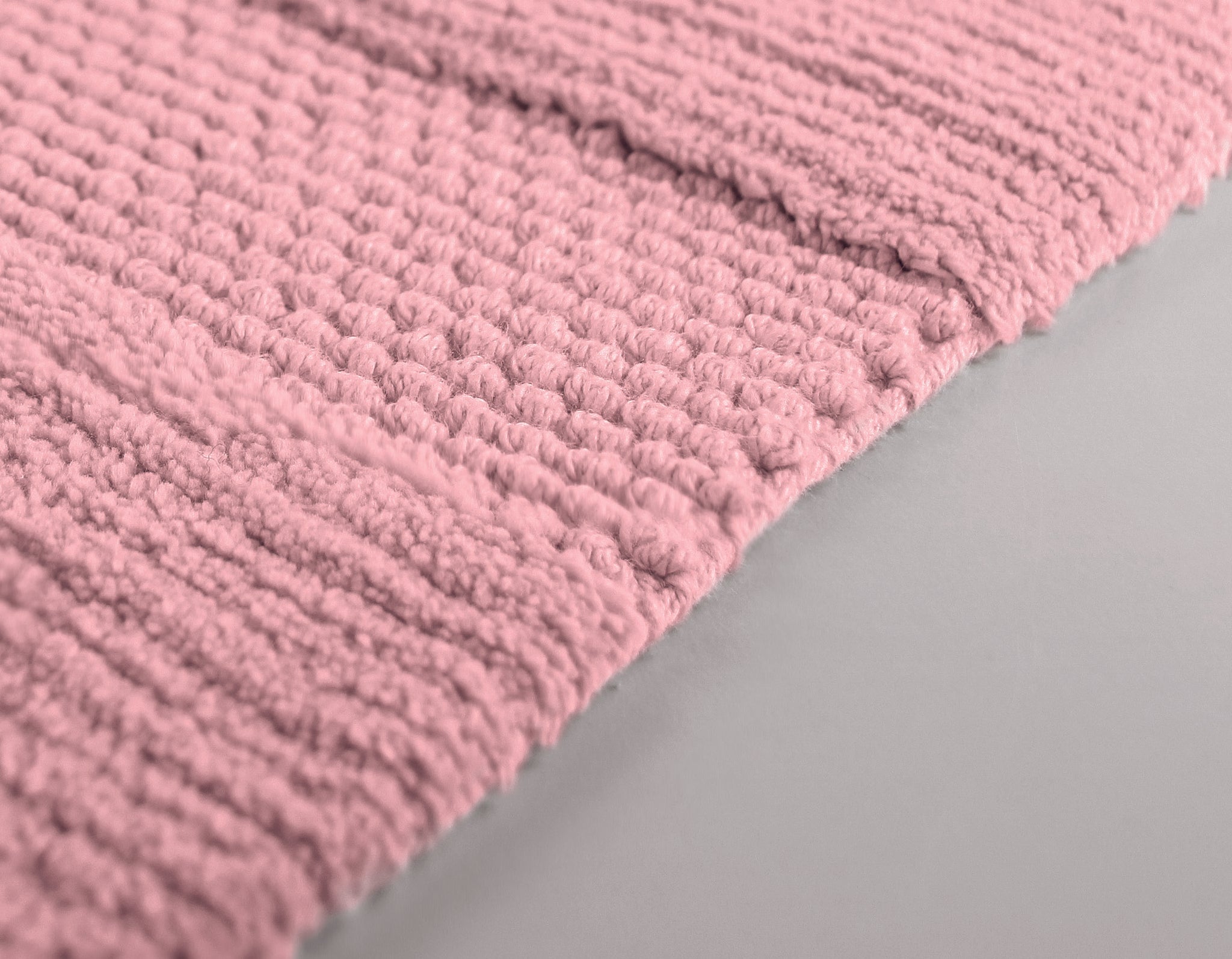 Nahaufnahme einer rosa, dick strukturierten Badematte auf hellem Boden