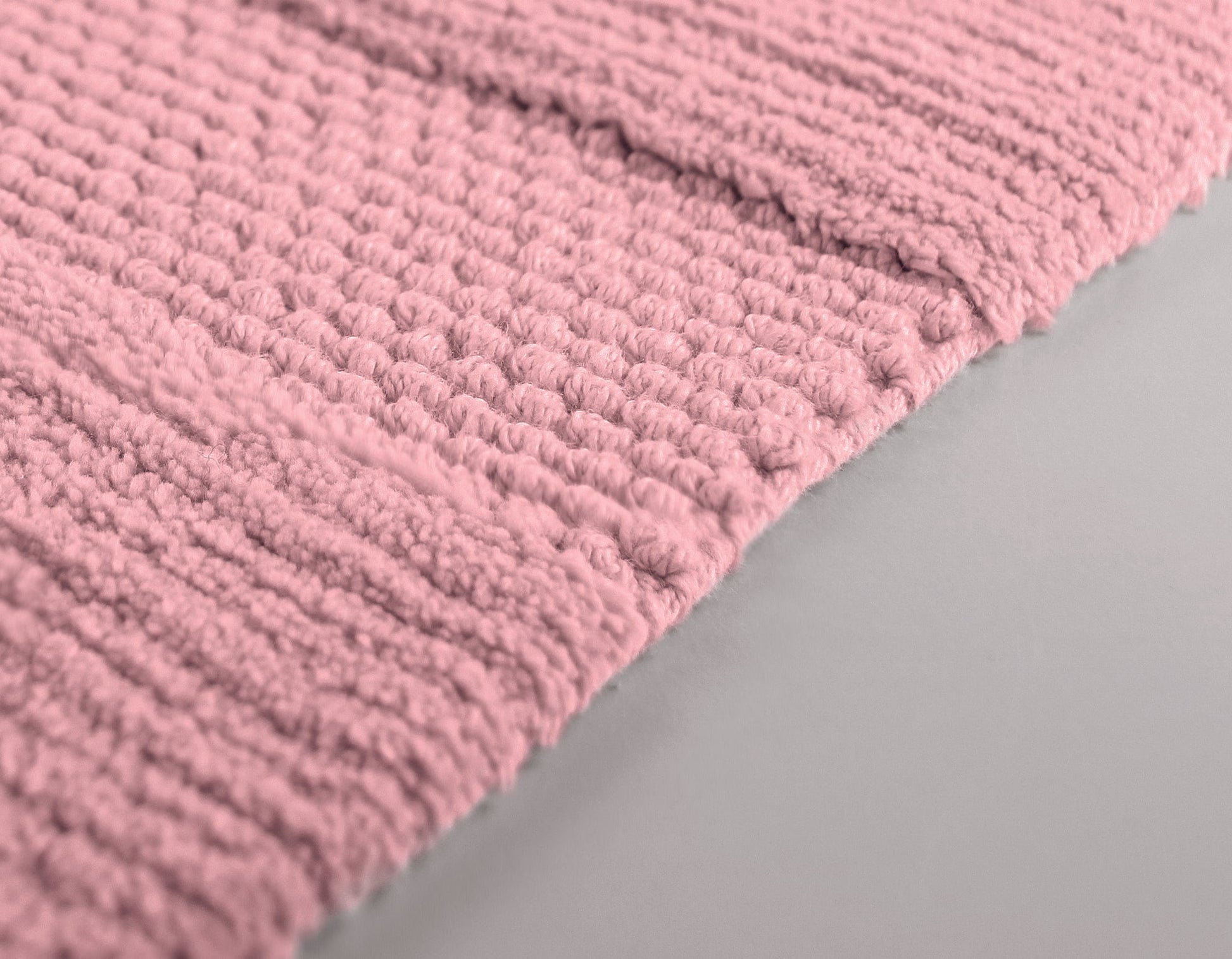 Detailansicht einer rosa Badematte mit grober, gerippter Struktur