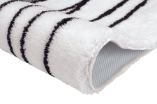 Nahaufnahme weißer Badteppich mit schwarzen Streifen und Gummirückseite