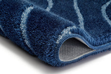 Nahaufnahme blauer Badematte mit Wellenmuster und umgeschlagener Ecke