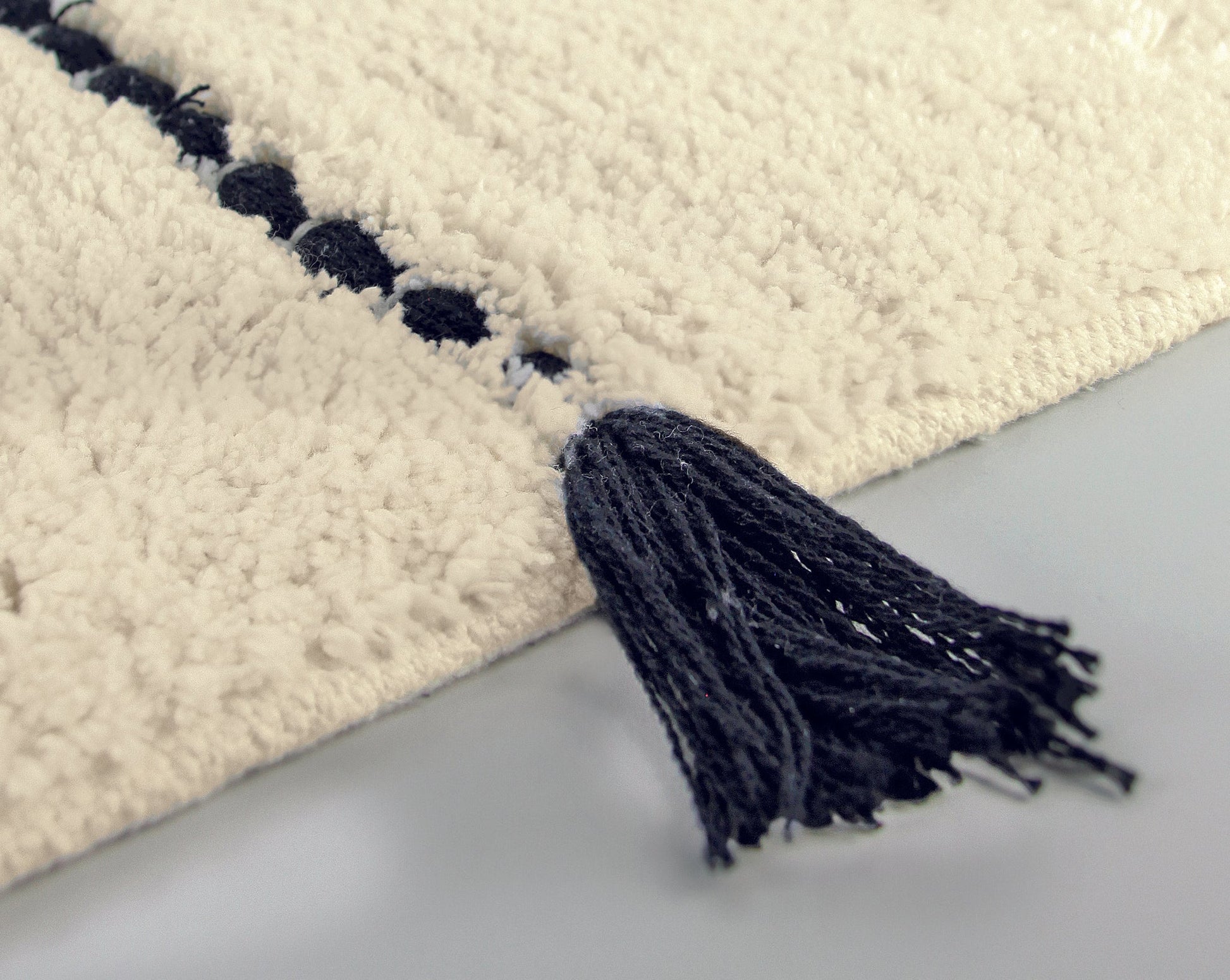 Badteppich TRAVIS Natur 55 x 65 cm zeigt Nahaufnahme mit dunklem Quastenabschluss.