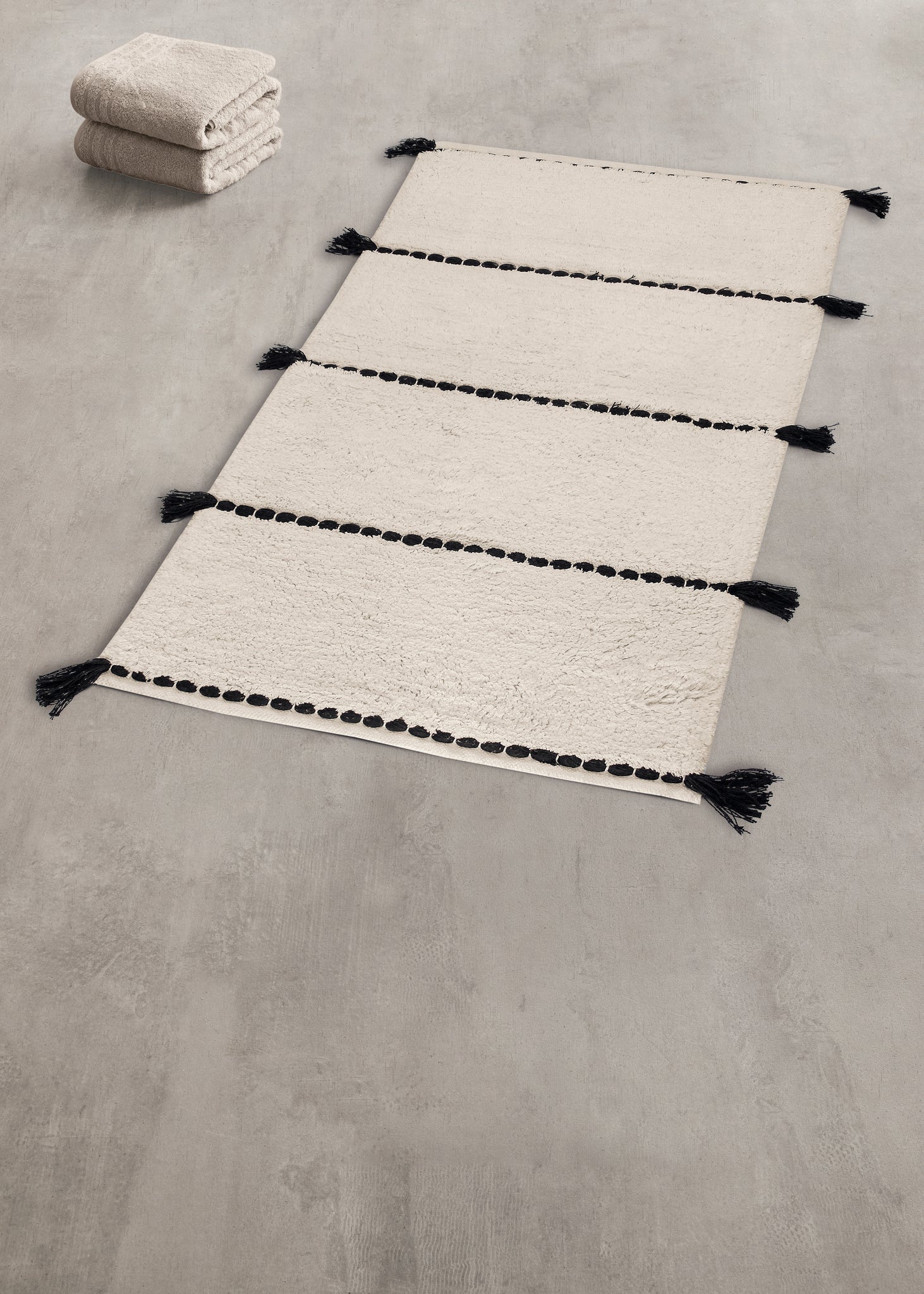 Badteppich TRAVIS Natur 80x140 cm liegt ausgelegt auf grauem Badezimmerboden.